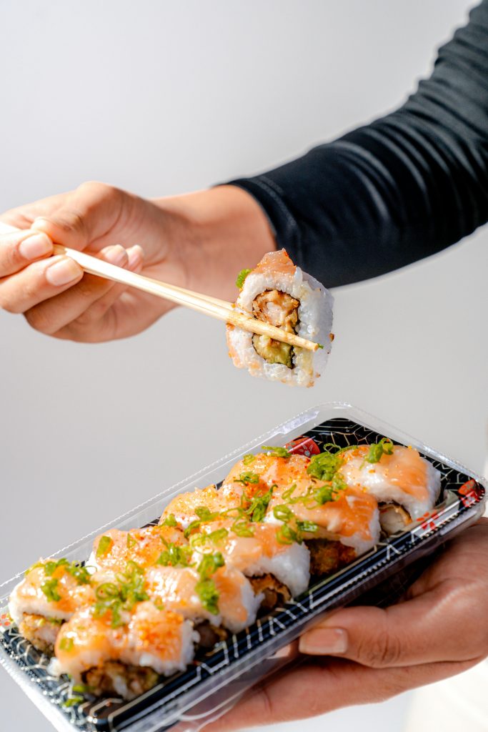 Appetizing sushi roll with salmon and avocado, served with chopsticks. Perfect for a fresh culinary experience.